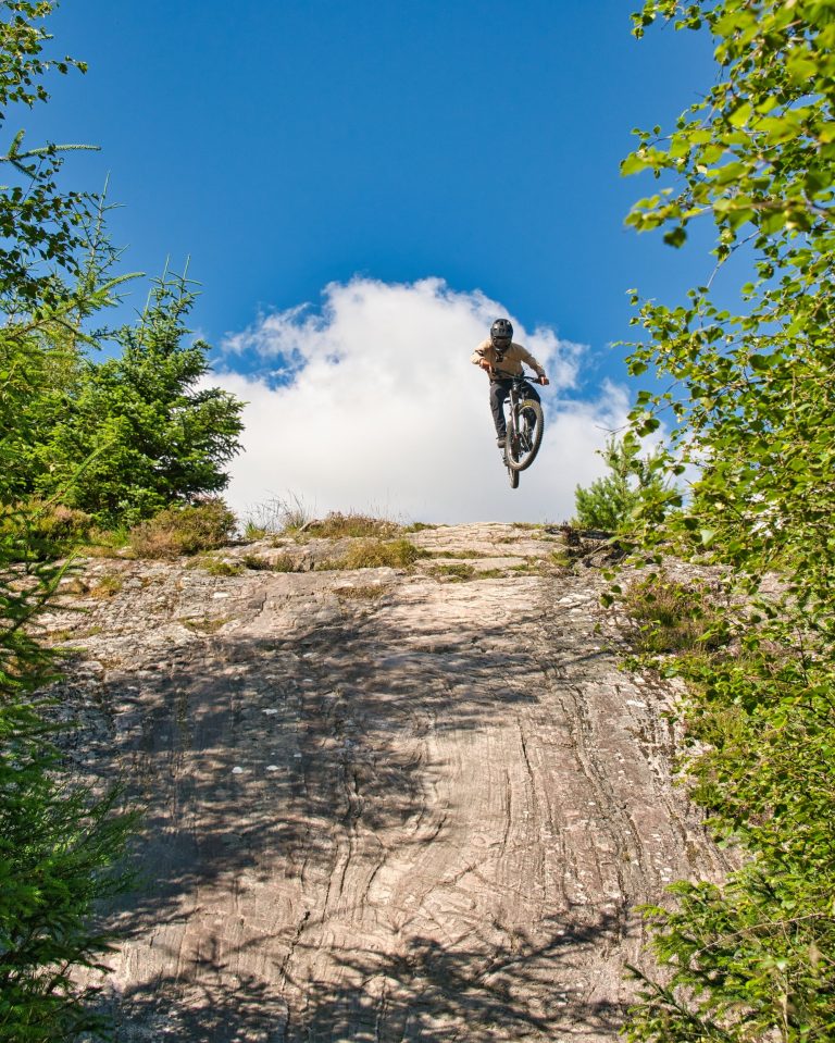Joel auf einem Mountainbike springt einen Fels hinunter